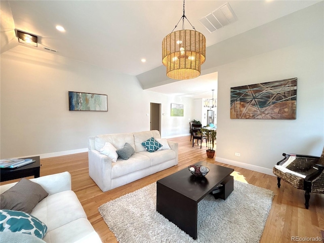 living room featuring baseboards, visible vents, a notable chandelier, and wood finished floors