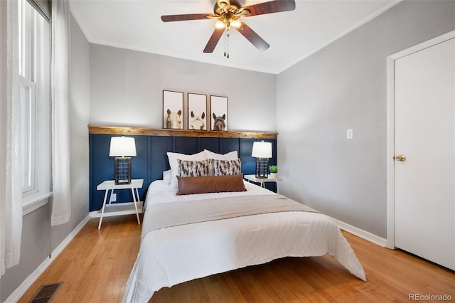 bedroom featuring ceiling fan, crown molding, and wood-type flooring