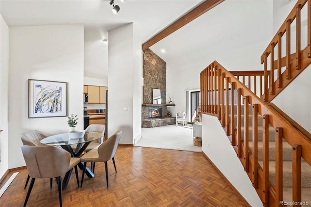 501 Manhattan Dr Unit 202, Boulder, CO 80303 - dining area with high vaulted ceiling, stairs, a fireplace, baseboards, and beam ceiling