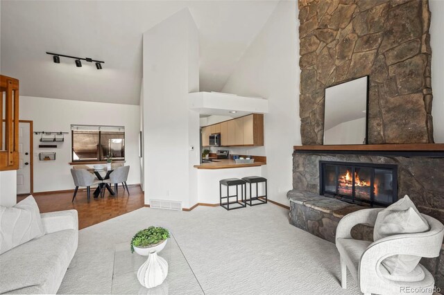 501 Manhattan Dr Unit 202, Boulder, CO 80303 - carpeted living area with rail lighting, baseboards, a fireplace, and high vaulted ceiling