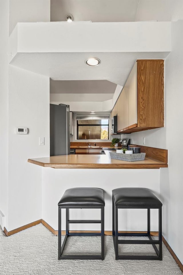 501 Manhattan Dr Unit 202, Boulder, CO 80303 - kitchen featuring a peninsula, baseboards, carpet, and freestanding refrigerator
