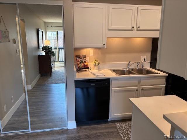 kitchen with sink, white cabinetry, black dishwasher, and dark wood-type flooring