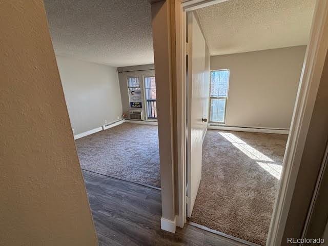 corridor with dark carpet and a textured ceiling