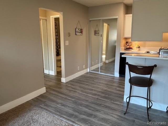 kitchen with white cabinetry, a breakfast bar area, and dark wood-type flooring