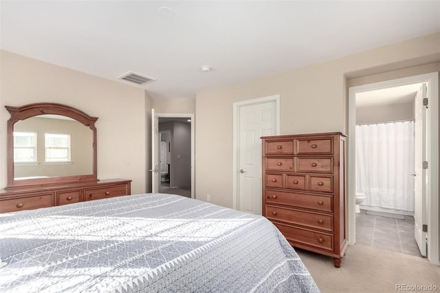 bedroom with connected bathroom and light colored carpet