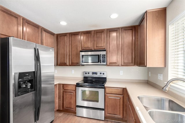 kitchen featuring sink, a wealth of natural light, stainless steel appliances, and light hardwood / wood-style floors