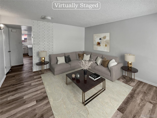 living room featuring dark hardwood / wood-style flooring, brick wall, and a textured ceiling