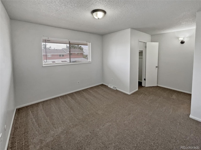 carpeted empty room featuring a textured ceiling