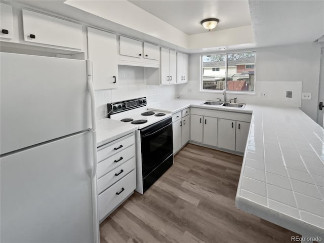 kitchen featuring white appliances, wood-type flooring, white cabinets, tile countertops, and sink