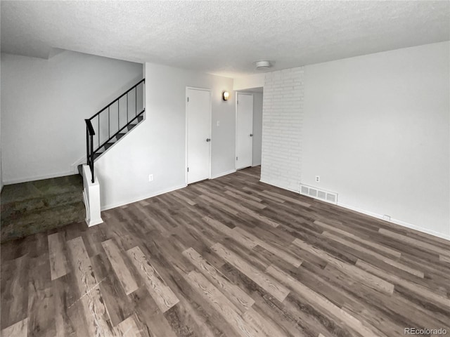 interior space featuring dark hardwood / wood-style floors, brick wall, and a textured ceiling