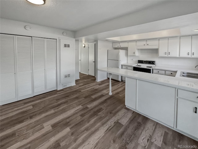 kitchen with tile counters, white appliances, white cabinets, dark wood-type flooring, and sink