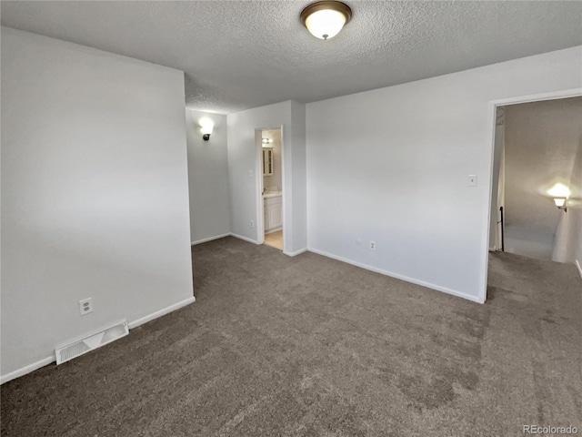 empty room with dark carpet and a textured ceiling