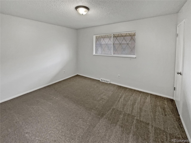 spare room with dark carpet and a textured ceiling