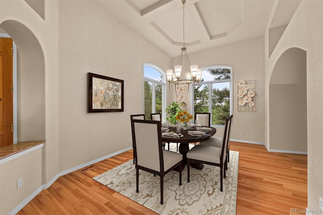 dining area featuring light hardwood / wood-style floors, coffered ceiling, and an inviting chandelier