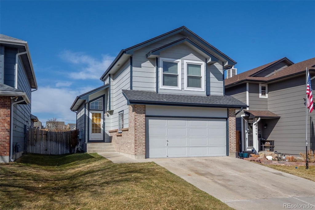 traditional home featuring brick siding, fence, concrete driveway, a front yard, and an attached garage