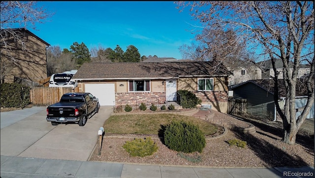 ranch-style home featuring concrete driveway, a garage, fence, and brick siding