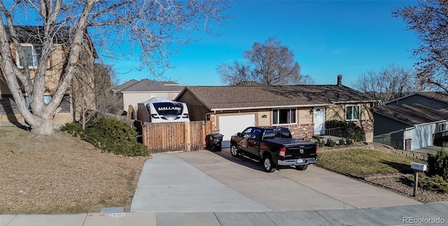 view of front of home with an attached garage, concrete driveway, and fence