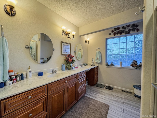 full bathroom with visible vents, baseboards, vanity, wood finished floors, and a textured ceiling