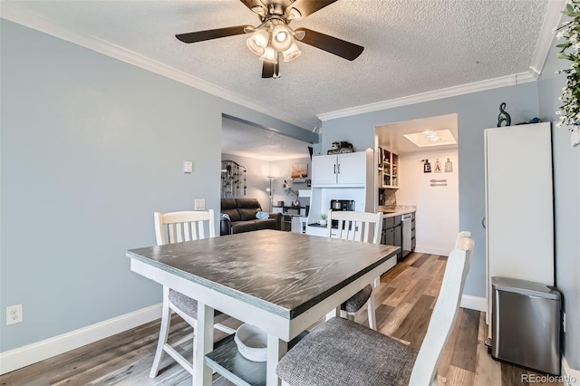 dining room featuring ceiling fan, wood-type flooring, ornamental molding, and a textured ceiling