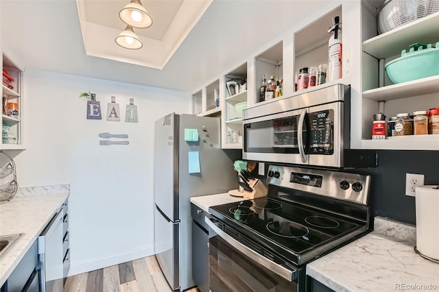 kitchen with sink, light hardwood / wood-style flooring, stainless steel appliances, light stone counters, and a raised ceiling