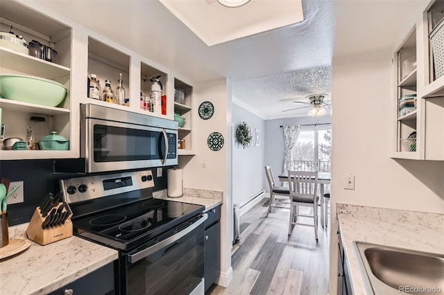 kitchen featuring light stone counters, a textured ceiling, appliances with stainless steel finishes, ceiling fan, and light hardwood / wood-style floors