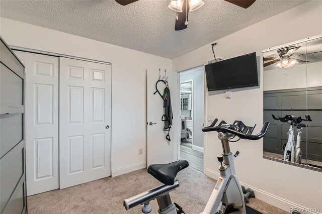 workout area with ceiling fan, light colored carpet, and a textured ceiling