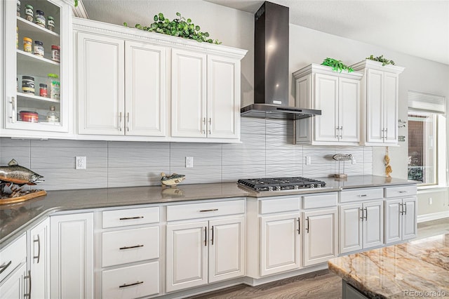 kitchen featuring wood finished floors, white cabinetry, wall chimney exhaust hood, and stainless steel gas stovetop