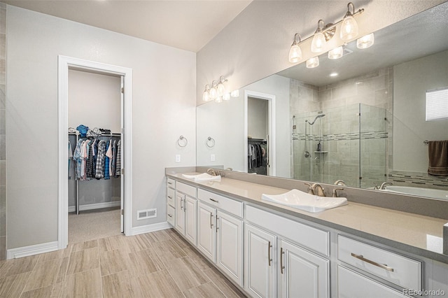 full bathroom featuring double vanity, a stall shower, visible vents, and a sink