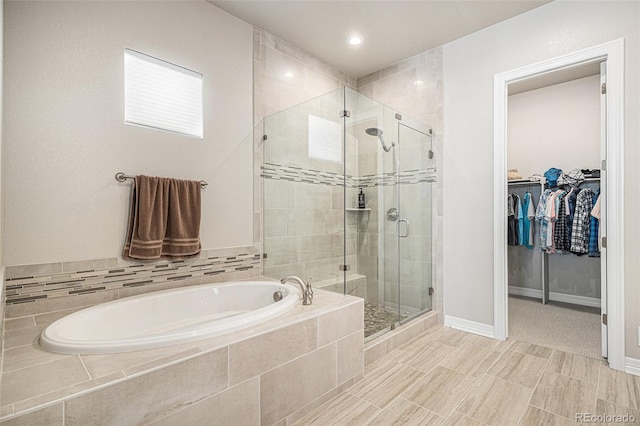 full bath featuring a stall shower, baseboards, a bath, and a spacious closet