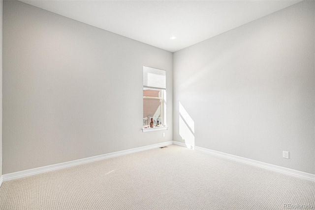 spare room featuring light carpet, visible vents, and baseboards