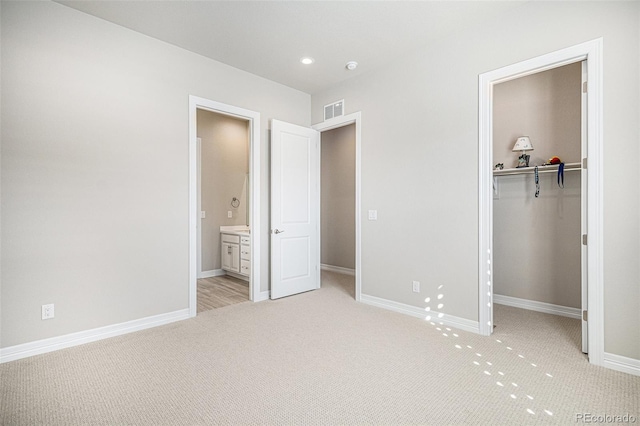 unfurnished bedroom featuring visible vents, light carpet, a closet, baseboards, and a spacious closet