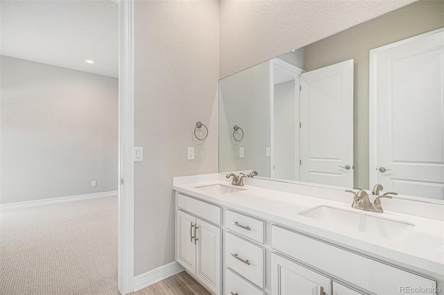 bathroom with double vanity, baseboards, and a sink