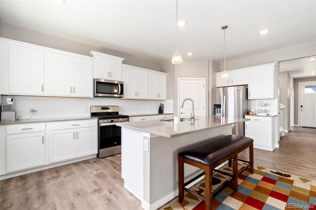 4209 Fox Grove Dr, Fort Collins, CO 80524 - kitchen with appliances with stainless steel finishes, a sink, light wood-style flooring, a kitchen breakfast bar, and tasteful backsplash