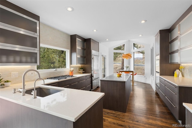 kitchen featuring a center island, backsplash, a sink, and dark brown cabinets