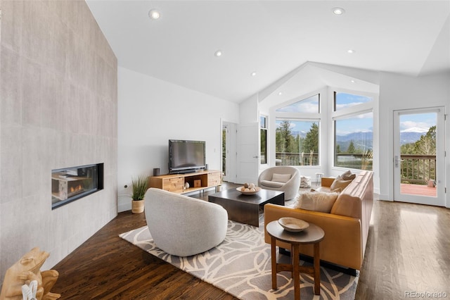 living area with recessed lighting, high vaulted ceiling, a fireplace, and wood finished floors
