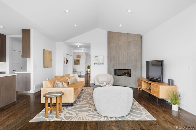 living area featuring vaulted ceiling, recessed lighting, a tile fireplace, and dark wood-type flooring