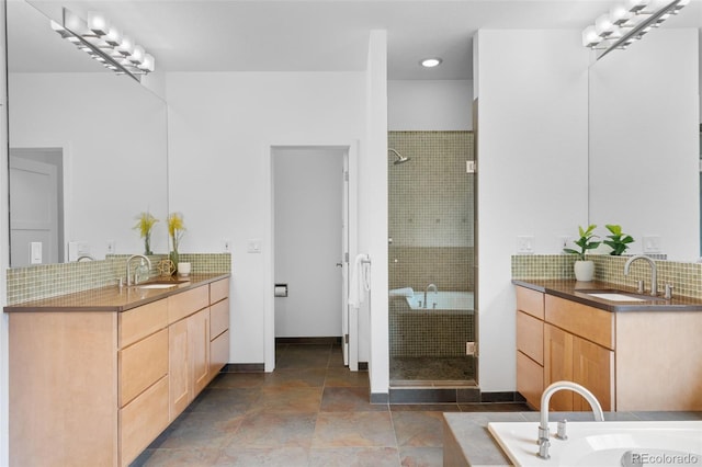 bathroom with a sink, a stall shower, and backsplash