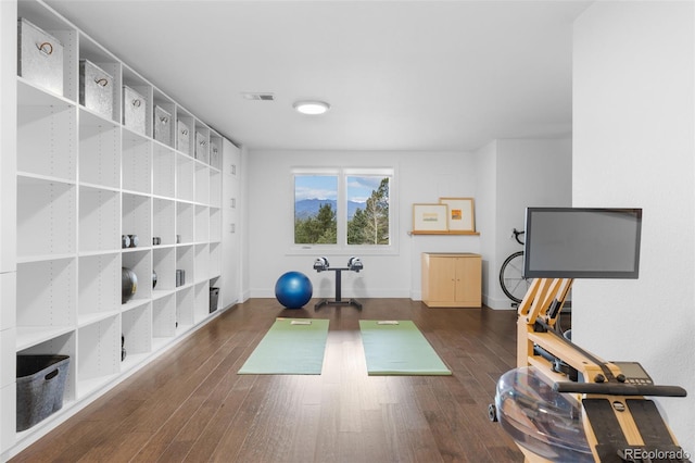 workout area with visible vents, baseboards, and wood finished floors