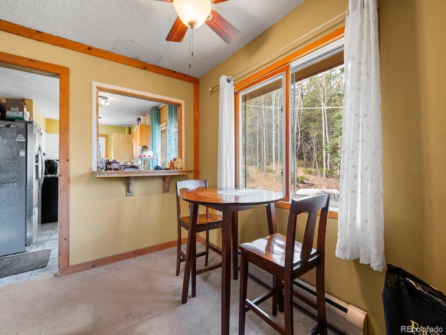 dining area featuring ceiling fan, a textured ceiling, a baseboard radiator, and light colored carpet