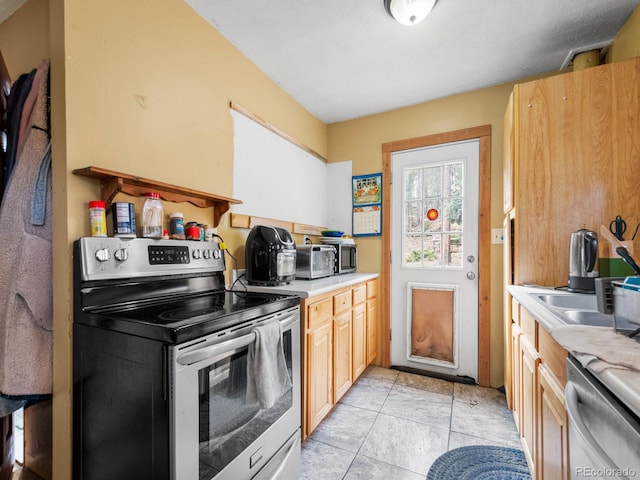 kitchen with light brown cabinetry, stainless steel appliances, and light tile patterned floors