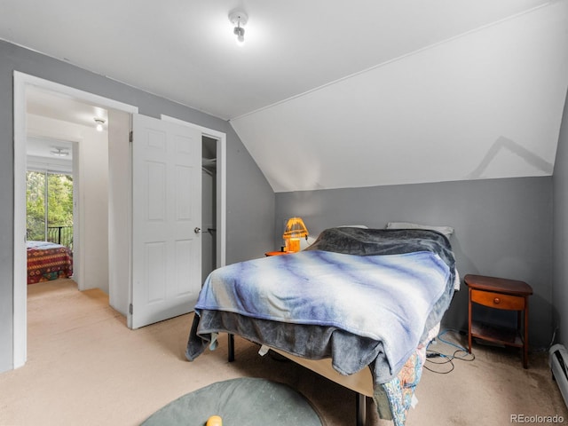 bedroom featuring lofted ceiling, a baseboard heating unit, and light carpet