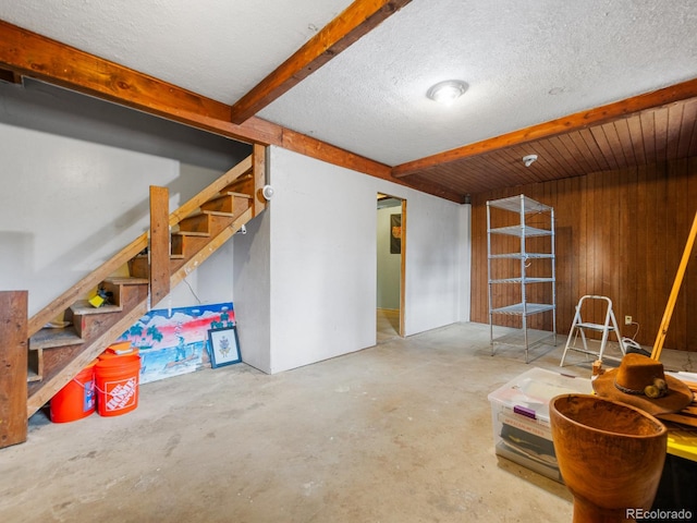 basement featuring a textured ceiling and wood walls