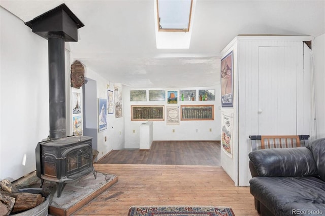 living area featuring a wood stove, a skylight, and wood finished floors