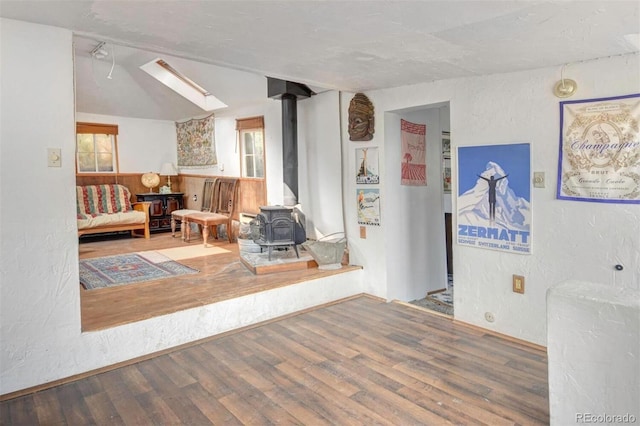 interior space with a wood stove, a textured wall, and wood finished floors