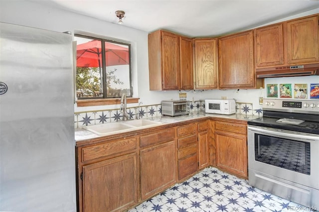 kitchen with stainless steel range with electric stovetop, under cabinet range hood, a sink, white microwave, and light floors