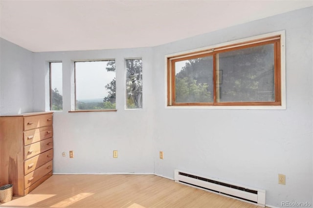 empty room with light wood-type flooring and a baseboard heating unit