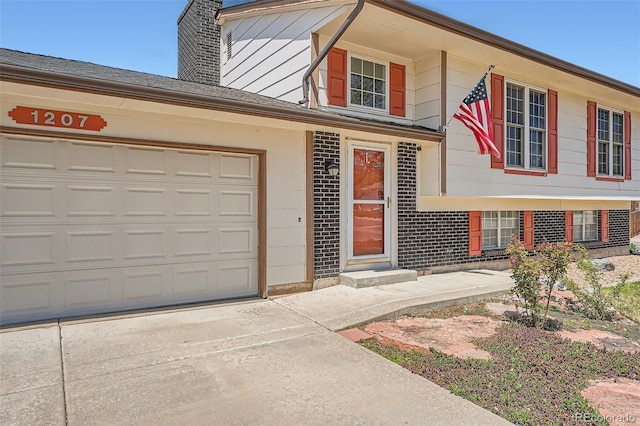 view of front facade featuring an attached garage, concrete driveway, brick siding, and a chimney