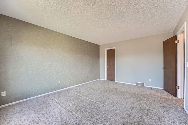 empty room with visible vents, carpet flooring, a textured ceiling, and baseboards