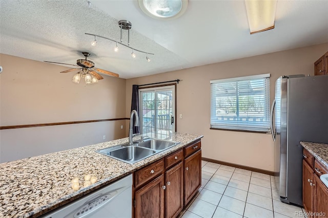 kitchen with track lighting, freestanding refrigerator, ceiling fan, a sink, and dishwasher