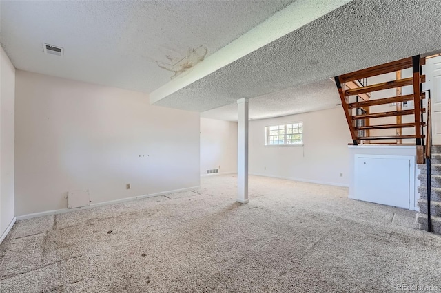 below grade area featuring baseboards, a textured ceiling, and visible vents